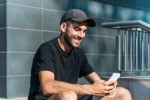 Happy man texting on smartphone on street