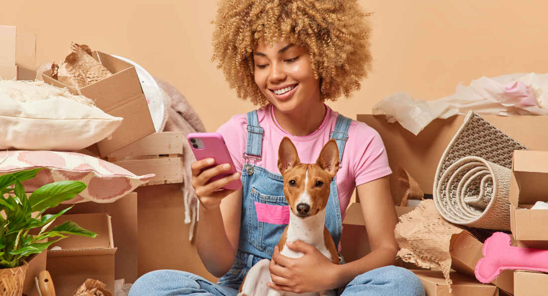 This image depicts a young woman looking at her phone while holding a dog.